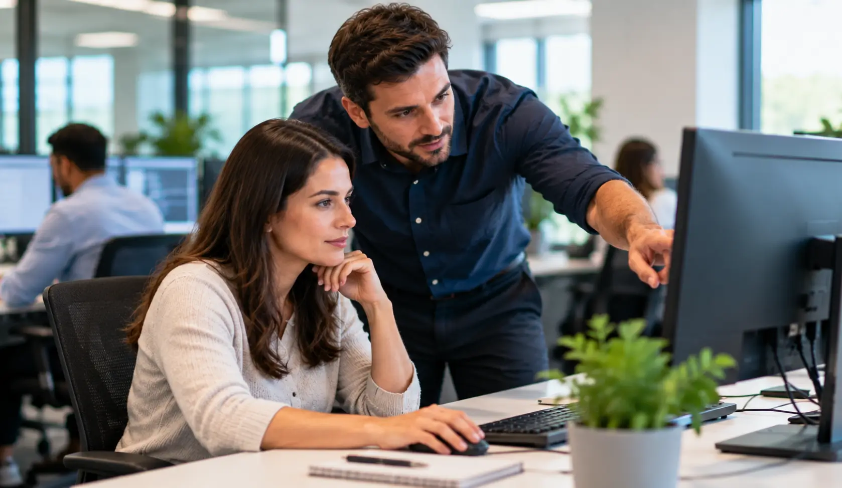 IT support professional helping an employee at a computer in an office